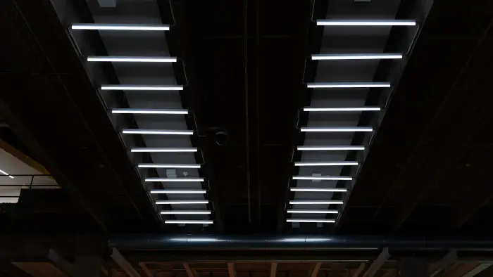 Rows of bright linear LED fixtures across a dark industrial ceiling